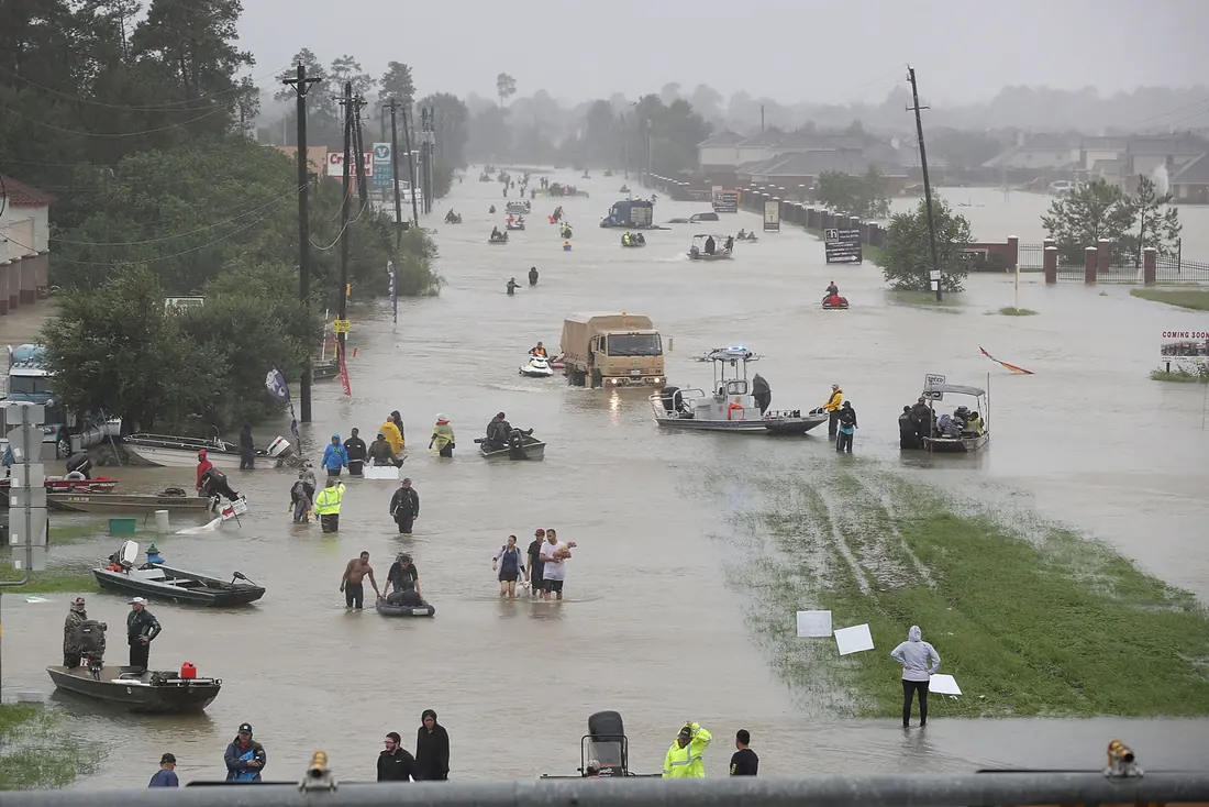 Flooded street after a storm, with small boats moving between houses