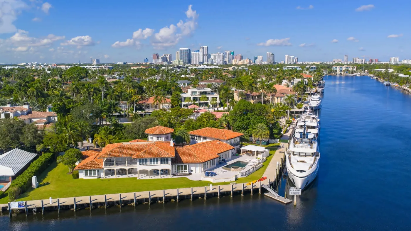 Waterfront Fort Lauderdale estate with a superyacht at its dock and the downtown skyline behind