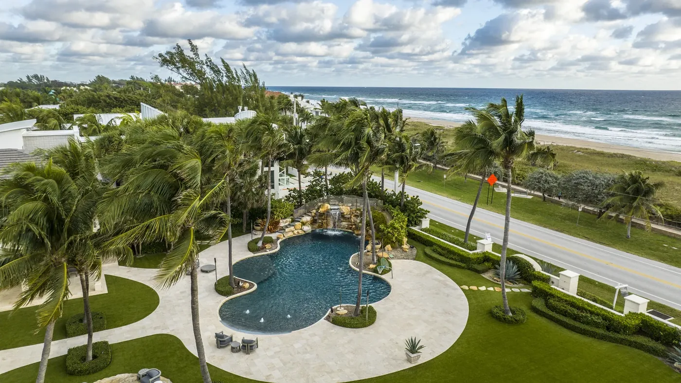 A resort pool and palms at first light with the ocean behind