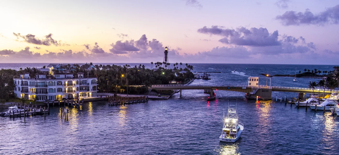 Lighthouse and bridge at an inlet during the blue hour, boats working the channel
