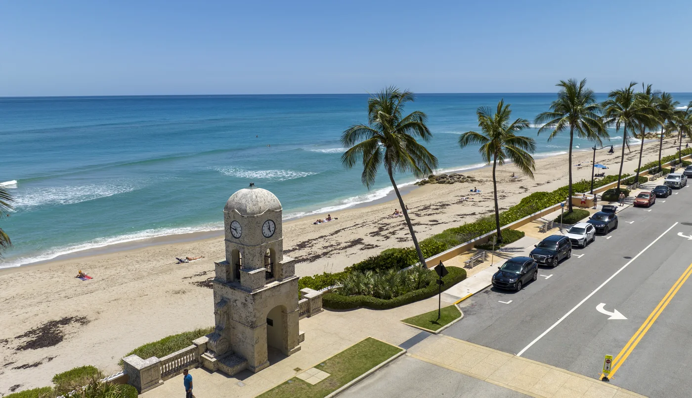 The Palm Beach clock tower from low and close, with the palm line and the road beside it