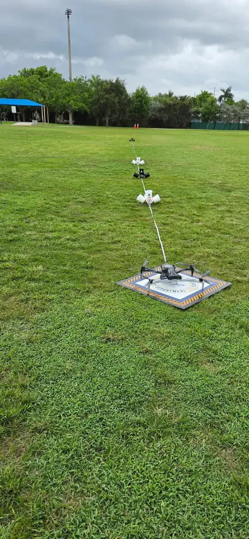 Drone on a fire department landing pad with a measured NIST standard test method lane running out across the field