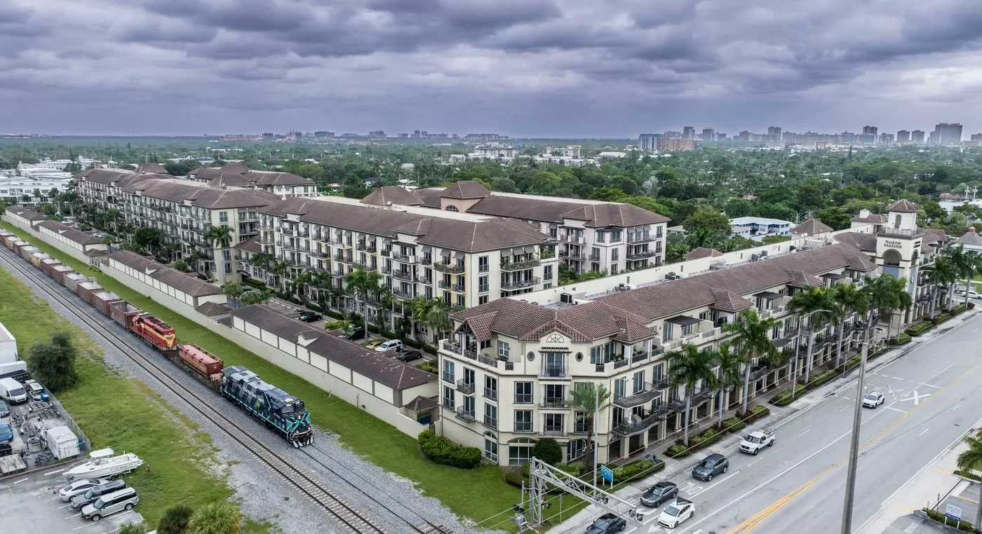 Freight train running past a Mediterranean-style condominium development in Wilton Manors